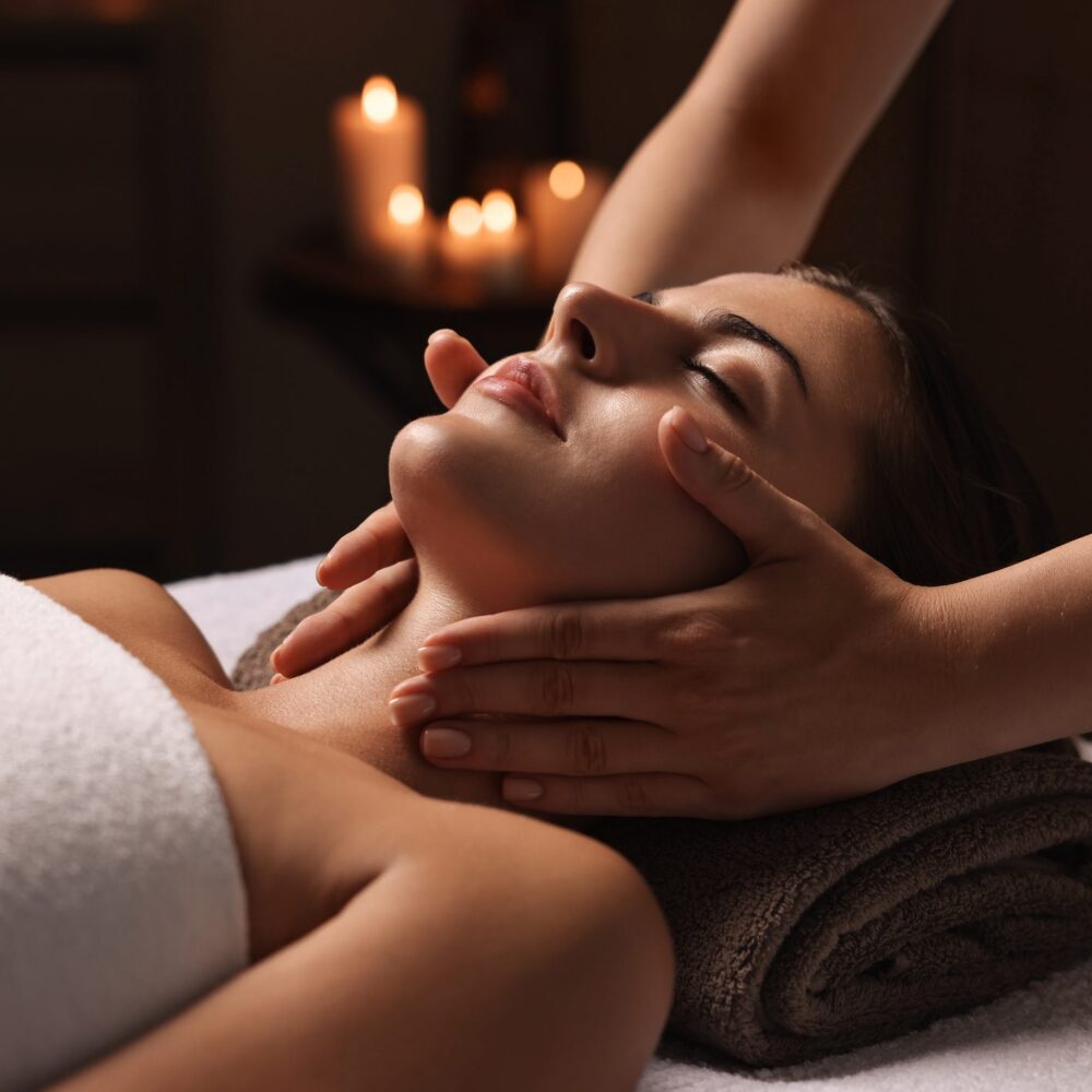 Hands massaging woman's face on towel